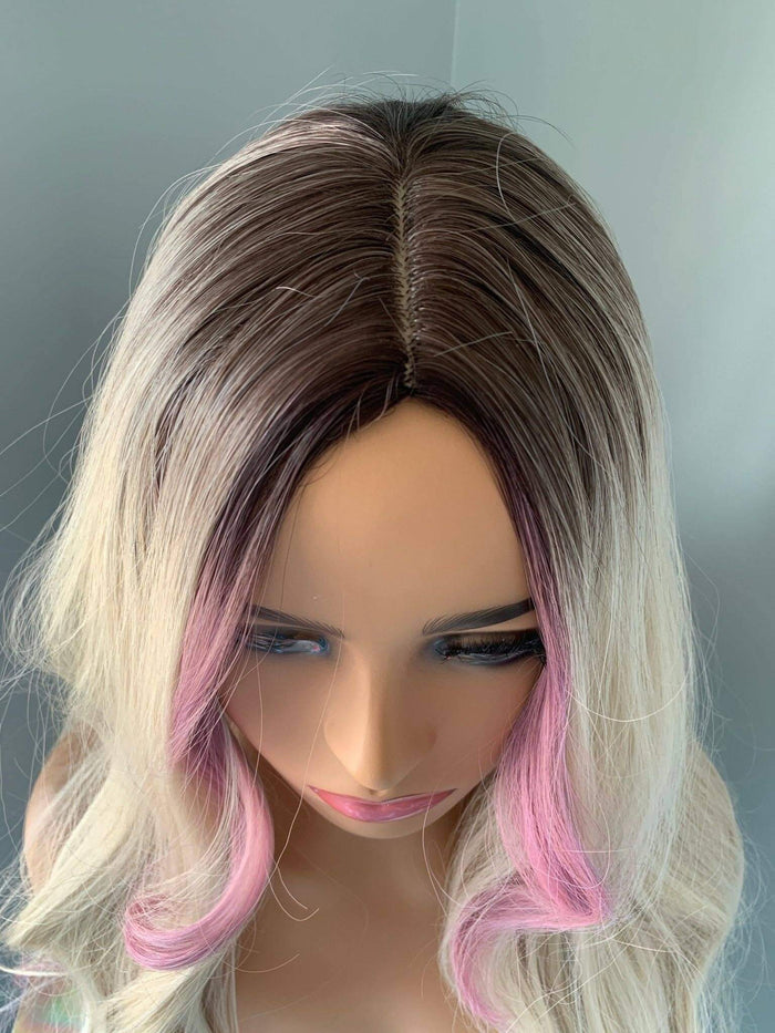 Mannequin head with a wig featuring a gradient from pink to blonde hair on a plain background.