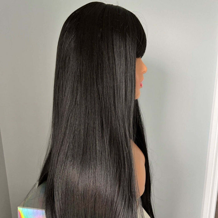 Black wig on a mannequin head against a plain background
