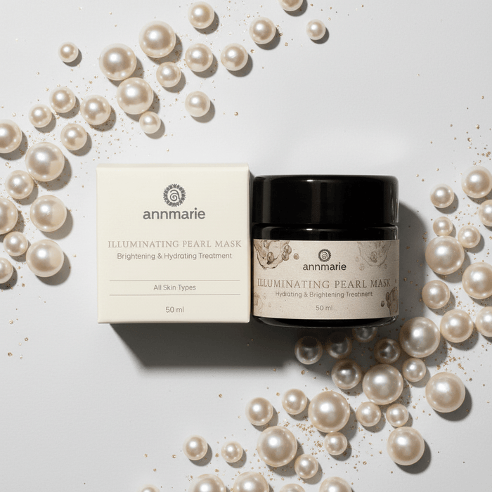 Annmarie Illuminating Pearl Mask with packaging surrounded by pearls on a light background