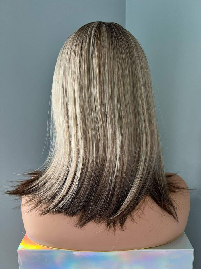 Back view of a sleek Jenna Short Rooted Blonde Wig with Low Lites, showcasing smooth, layered hair.