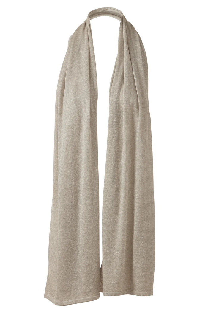 A woman with long, wavy blonde hair displays the drape and texture of the KINROSS CASHMERE Linen Lurex Wrap in light beige while wearing white pants against a plain white background.