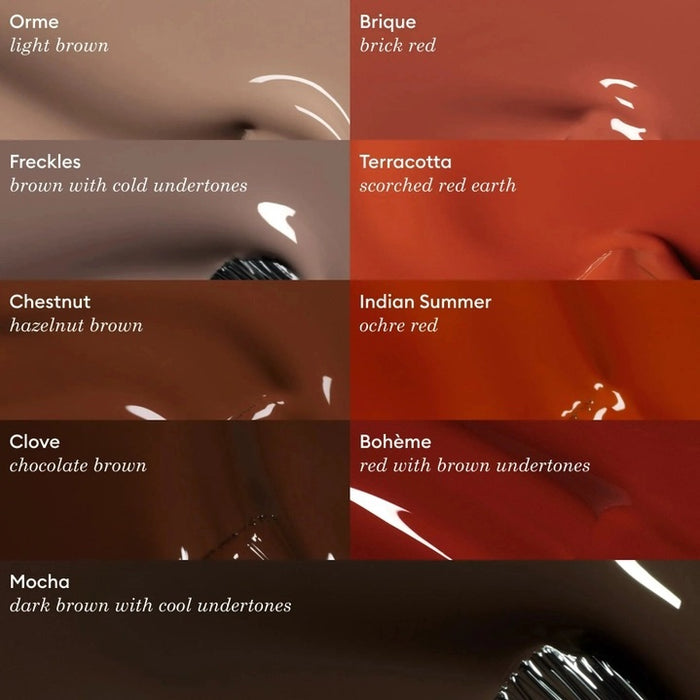 A hand with short nails painted in MANUCURIST - GREEN™ Nail Polish in Mocha by MANUCURIST INC rests on a shiny, metallic, wavy-edged object against a deep red background.