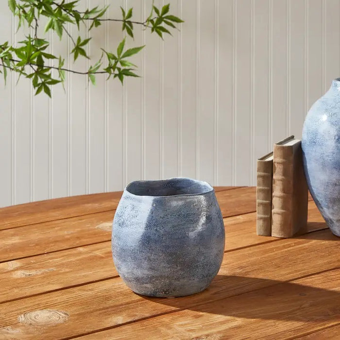 The NAPA HOME AND GARDEN - CASPIAN CACHEPOT is a round, blue ceramic vase with a glossy, mottled finish and speckled pattern—ideal for decorative use on any shelf or table.