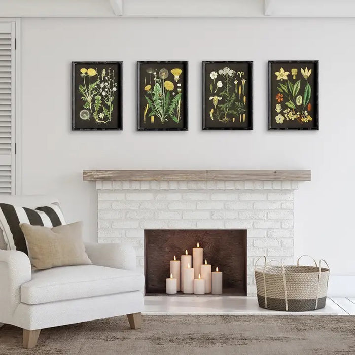 A cozy living room features a white armchair, neutral pillows, a basket, a white brick fireplace with candles inside, and four NAPA HOME AND GARDEN Golden Botanical Study wall art prints above the mantel.