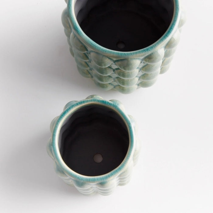 The NAPA HOME AND GARDEN - VALENCIA POT, LARGE is a round ceramic planter by NAPA HOME AND GARDEN, featuring a glossy seafoam glaze and a raised, bubble-like pattern on the exterior. This contemporary planter is light grey-green in color and is shown empty against a white background.