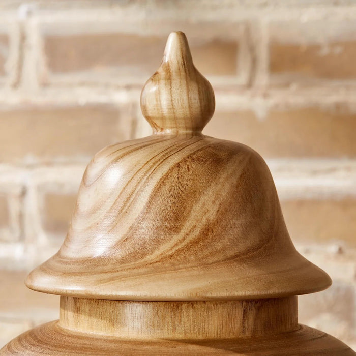 The PAULOWNIA WOOD COVERED TEMPLE JAR - SMALL by TWO'S COMPANY features a light brown paulownia wood construction with a rounded body, subtly narrow base, and a decorative lid. Its visible wood grain offers a natural and smooth look, making it an exotic accent piece for the home. The jar is shown standing upright against a white background.
