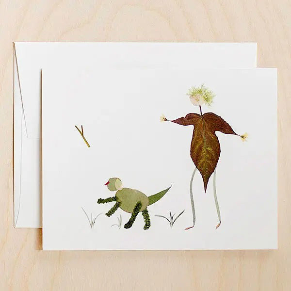 The PETAL PEOPLE PRESS - FETCH CARD by PETAL PEOPLE PRESS features a dog lover design made from leaves and twigs, showing a person throwing a stick for a dog with grass details—an ideal card for any occasion.