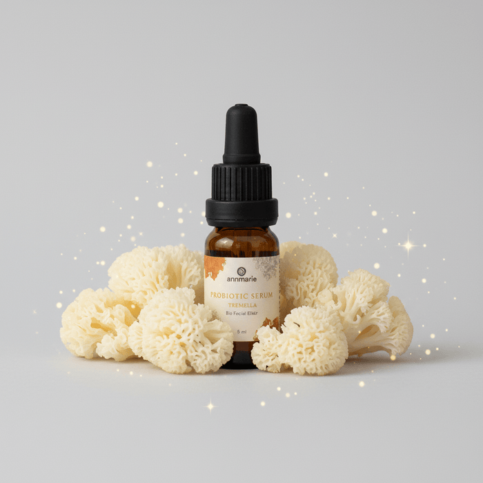 Bottle of skincare serum with a dropper on a light gray background with white flowers.