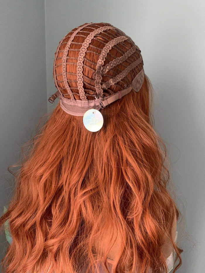 Back view of a Riri Long Red Auburn Loose Curls Wig showing its cap construction and flowing auburn waves.