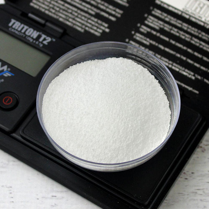 A white powder rests in a clear dish on a black digital scale labeled "TRITON T2 CAPACITY 150g 0.1g".