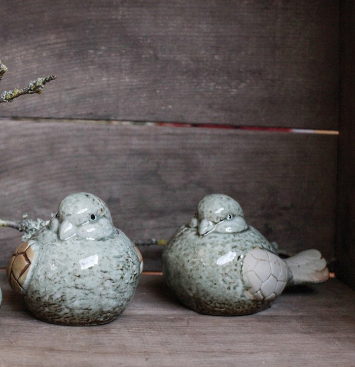 The CREATIVE COOP STONEWARE BIRD set features two figurines with green and beige textured reactive glaze finishes, facing each other against a white backdrop—an ideal decorative accent for any space.