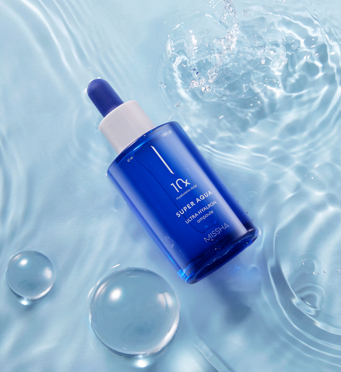 MISSHA Super Aqua Ultra Hyalron Ampoule in a sleek blue glass bottle resting on rippling water, with droplets and reflections emphasizing its deep hydration and moisture-boosting properties.