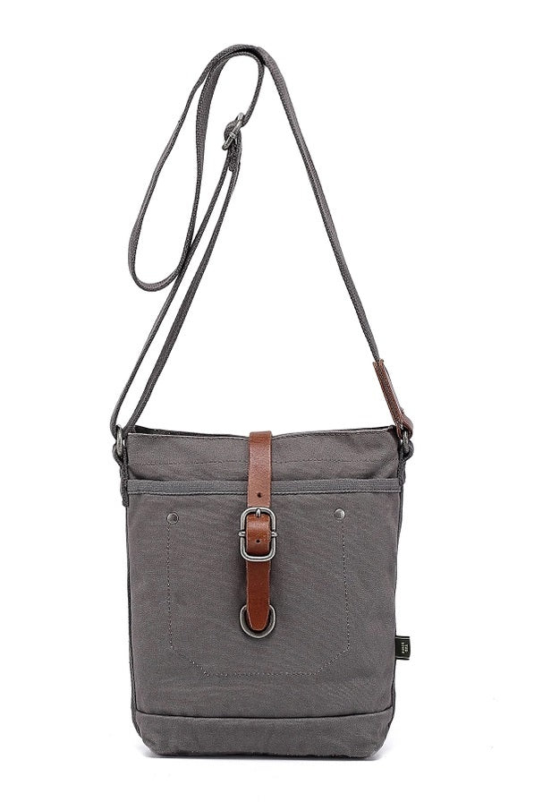 The TSD BRAND Forest Zip Crossbody Bag in Grey features a wide black strap, brown leather buckle accent, metal rivets, and a subtle side logo tag for a military-inspired look.