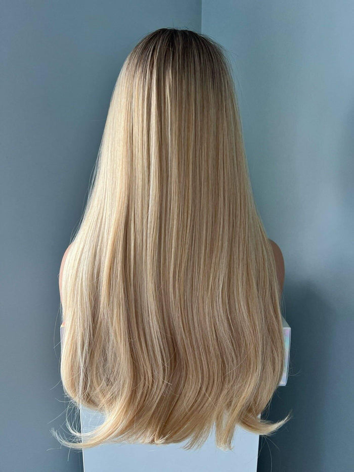 Mannequin head with long blonde hair against a light blue wall