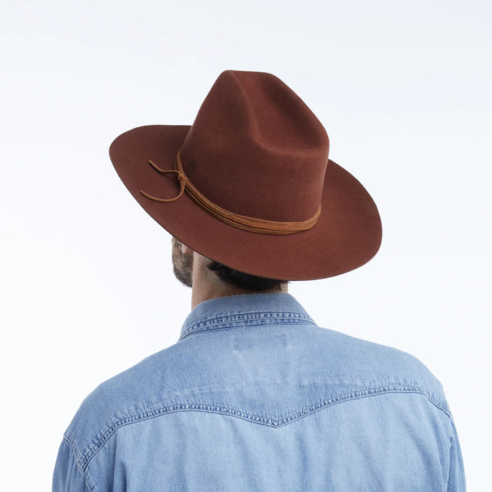 The WYETH Costa Cowboy Hat in Cinnamon features a wide brim, pinched crown, and thin suede trim tied in a bow. This adjustable hat by WYETH is shown on a white background.