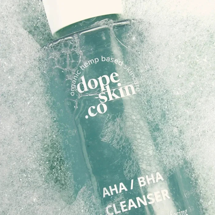 Dope Skin co AHA/BHA Cleanser bottle with water droplets on a light gray background