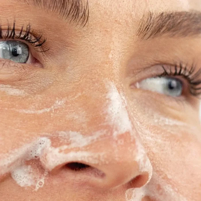 Close-up of a person's face with soap suds on their skin