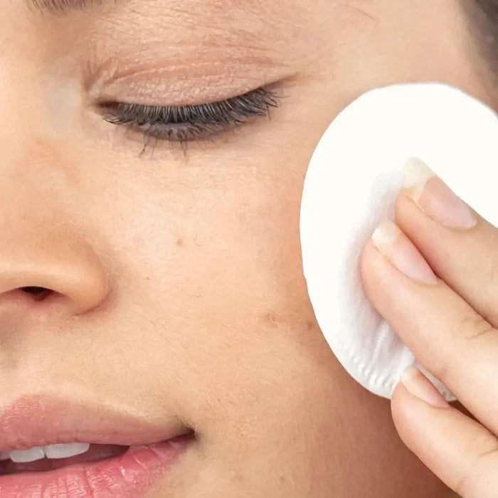 Person using a white cotton pad on their face