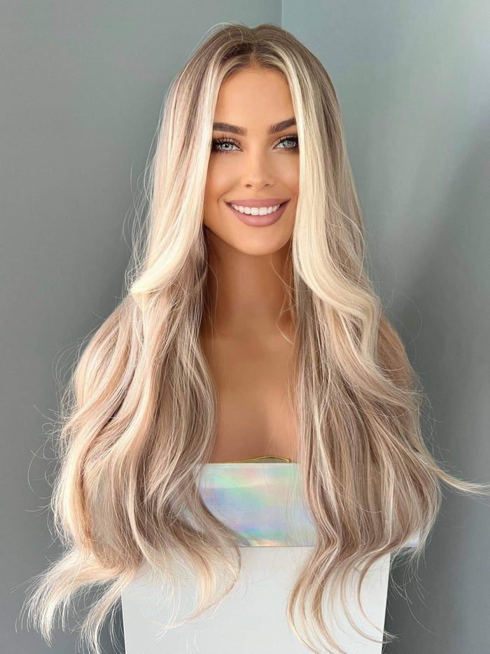 Woman with long, wavy blonde hair against a gray background