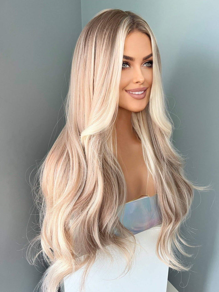 Woman with long, wavy blonde hair against a plain background