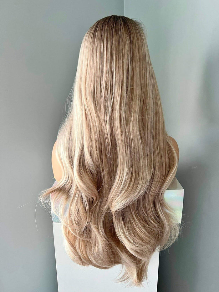 Blonde wig on a mannequin head against a plain background