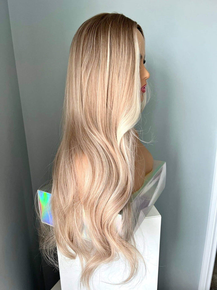 Blonde wig on a mannequin head against a plain background