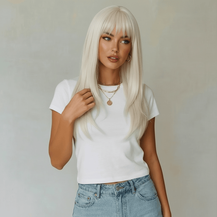 Woman with long blonde hair wearing a white t-shirt and blue jeans against a plain background