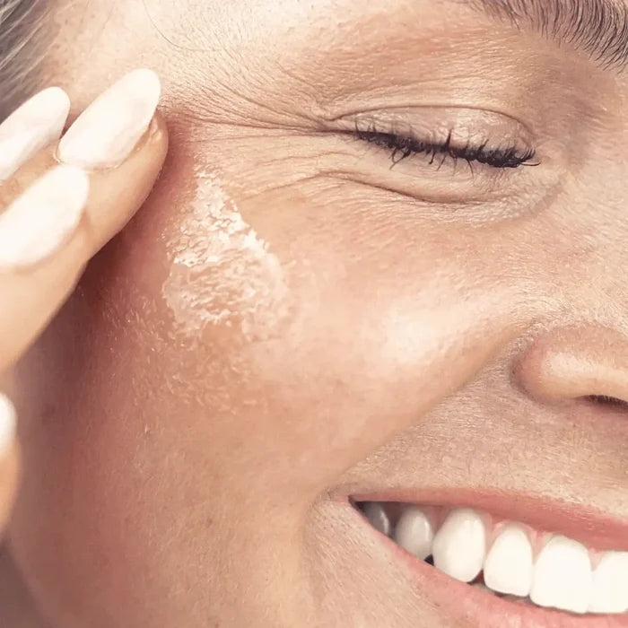 Close-up of a woman applying sunscreen to her face