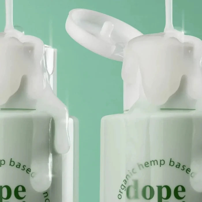 Two bottles of Dope Skin skincare product with droppers on a green background