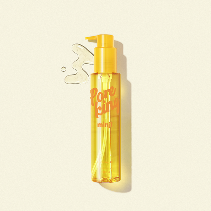 Minimalist product shot of A’pieu Pore King Minji Cleansing Oil in a transparent yellow pump bottle with golden liquid and spill detail on a light beige background, highlighting its clean and radiant look.
