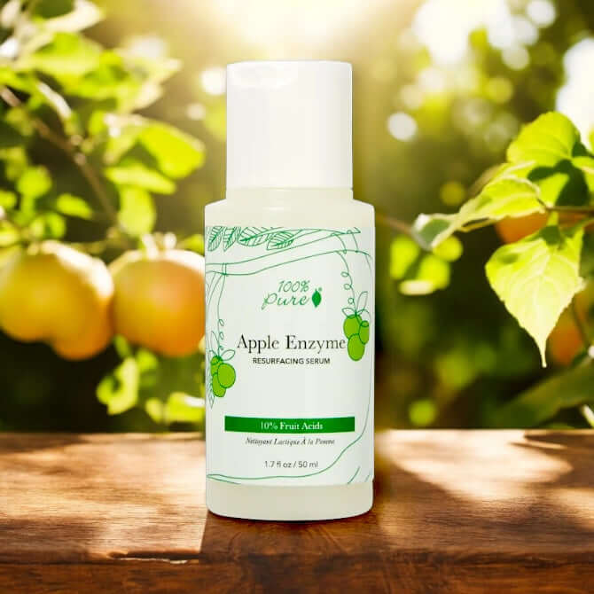 Apple Enzyme Resurfacing Serum bottle with 10% fruit acid, surrounded by greenery and apples.