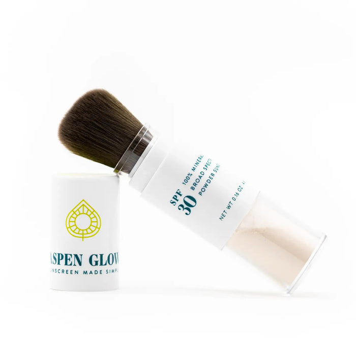 ASPEN GLOW offers a mineral sunscreen brush in a white-clear container with "Aspen Glow" text and logo. Featuring soft brown bristles, it applies translucent powder seamlessly for SPF 30 UV protection.