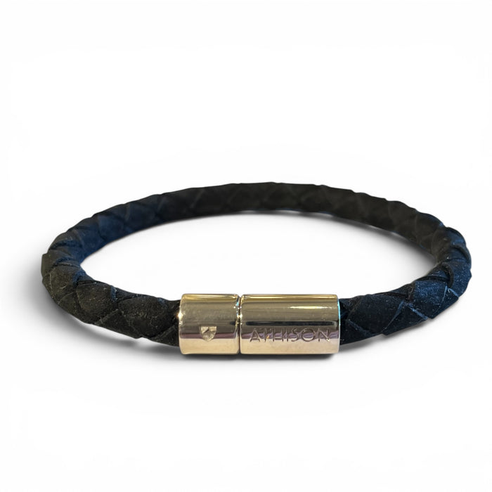 The ATHISON - BRAIDED NUBUCK BRACELET BLACK features a black braided design, crafted in Italy with a silver magnetic clasp engraved with text and a shield, shown on a white background.