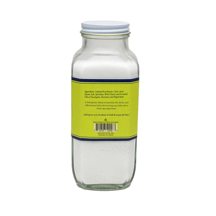 The BAUDELAIRE - BREATHE BATH SELTZER is a handmade 18 oz glass bottle with a yellow/green label, featuring an effervescent formula infused with eucalyptus and all-natural essential oils for a refreshing bath experience.