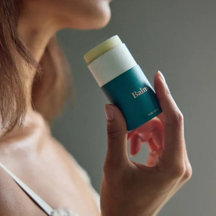 Person holding a blue balm container with a neutral background