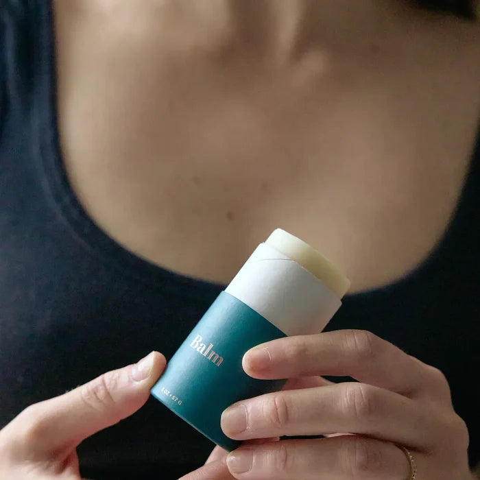 Person holding a stick of balm with 'balm' branding
