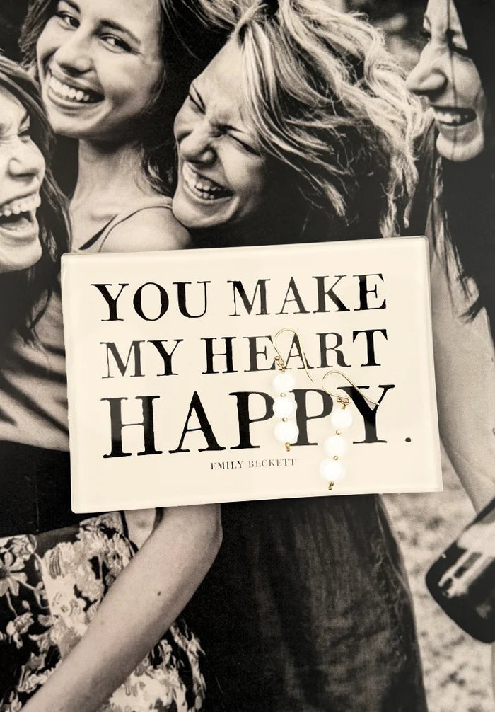 A cream-colored glass tray from BENS GARDEN features bold black lettering that reads, "YOU MAKE MY HEART HAPPY," with "EMILY BECKETT" inscribed below in smaller print. Reminiscent of the handcrafted style Ben’s Garden is known for, the BEN’S GARDEN - YOU MAKE MY HEART HAPPY DECOUPAGE GLASS TRAY makes a thoughtful gift or a charming accent for any space.