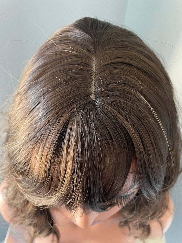 A close-up view of the top of a Bianca Short Dark Brown Wig with Bangs featuring soft waves and a natural look.