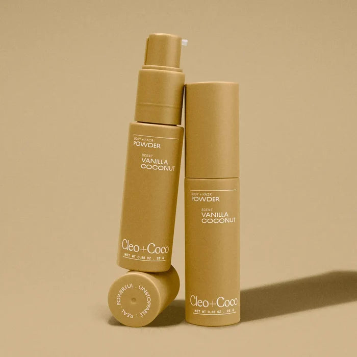 Three bottles of Cleo + CoCo body powder on a beige background