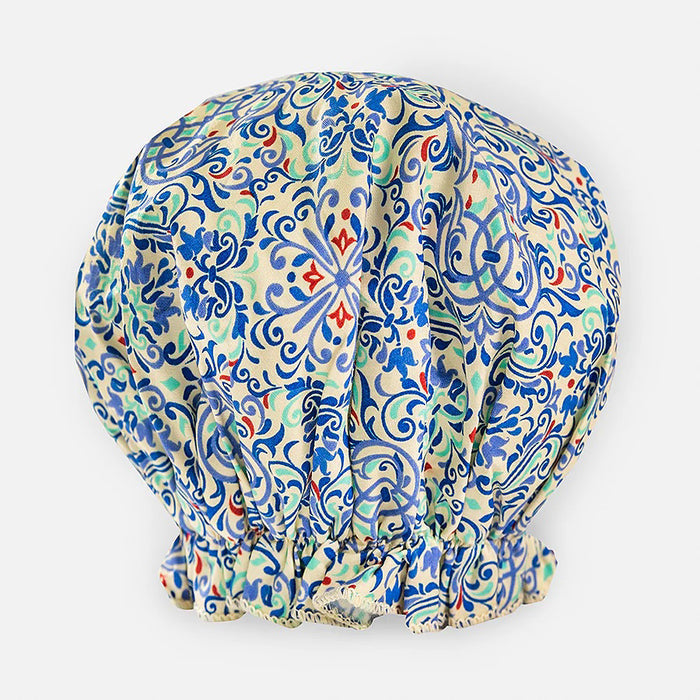 The BATH ACCESSORIES COMPANY's BOUFFANT SHOWER CAP - MORROCAN is a high-quality, waterproof cap with intricate floral and geometric patterns in blue, green, and red on a white background. It features an elastic-gathered bottom for a puffed shape.