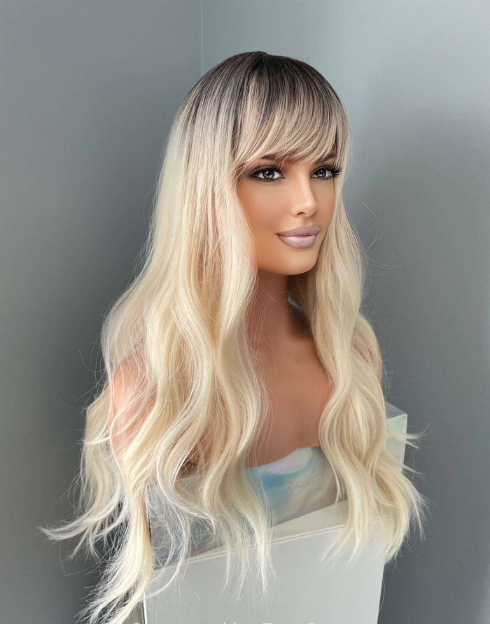 Mannequin head with long blonde wig against a plain background