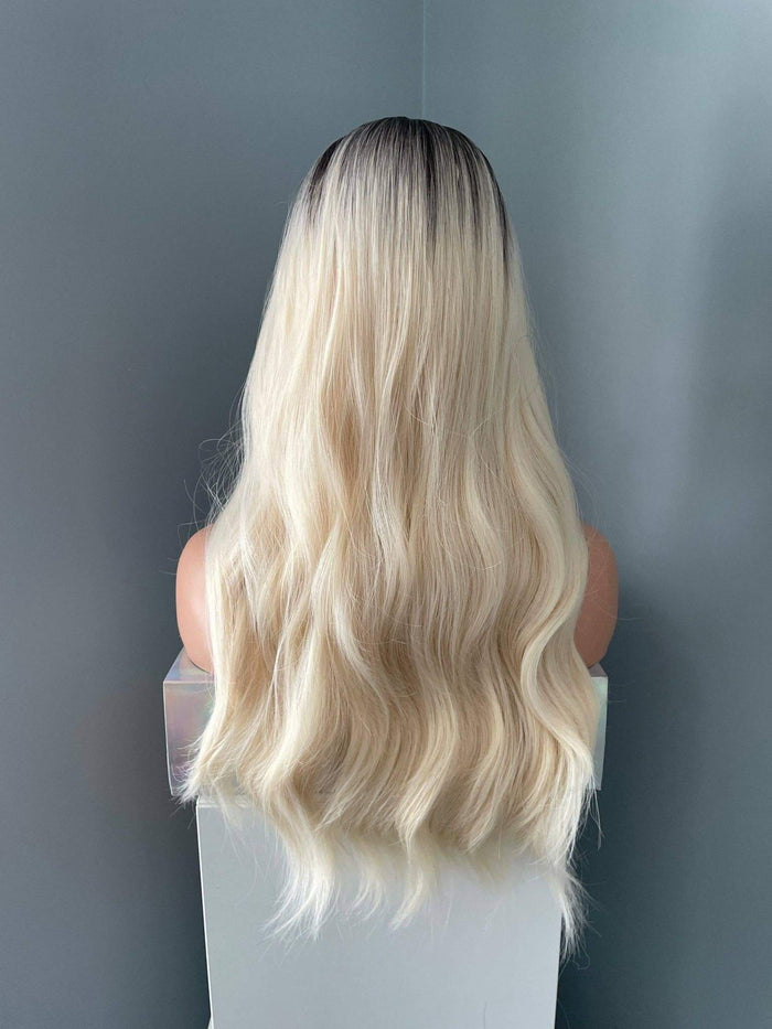 Blonde wig on a mannequin head against a plain background
