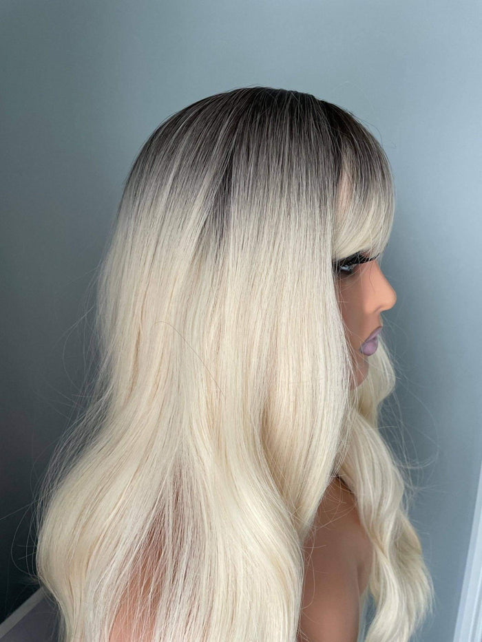 Woman with a blonde ombre wig against a gray background