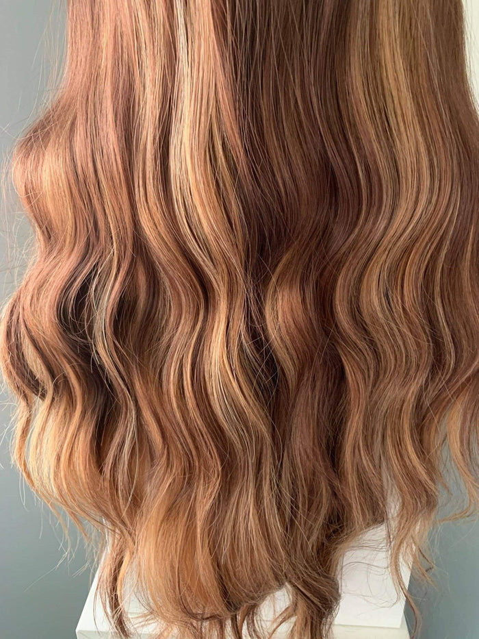 Close-up of wavy hair with brown and blonde tones on a neutral background