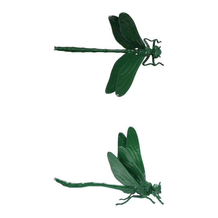 A pop-up book on a wooden surface showcases two large green CAST IRON DRAGONFLY sculptures by CREATIVE COOP, emerging from its pages against a plain light background.