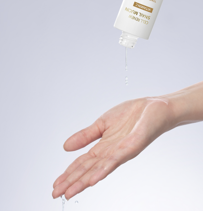 Close-up of Missha Cell Renew Snail Mucin Vitamin C Toner being poured from the bottle onto an outstretched hand, emphasizing the lightweight, watery texture and hydrating nature of the product.