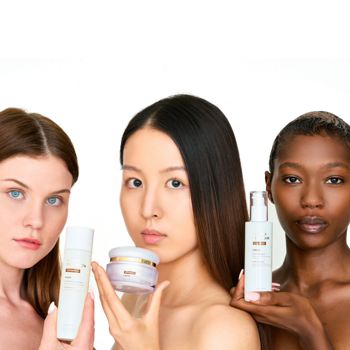 Three diverse models (White, Asian, and Black) holding various products from the Missha Cell Renew Snail Mucin Vitamin C line (Toner, Cream, and Ampoule), promoting the anti-aging Korean beauty products for all skin tones.