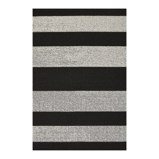 The CHILEWICH Black and White Bold Stripe Shag Doormat (18x28) rests on a light floor, with a pair of black flip-flops positioned to the right of the mat. Horizontal white wall panels provide a background.
