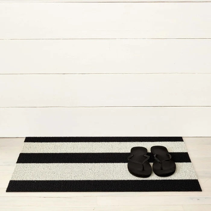 The CHILEWICH Black and White Bold Stripe Shag Doormat, measuring 18x28, features a rectangular design with alternating horizontal black and white stripes, offering an easy-care solution perfect for both indoor and outdoor use.