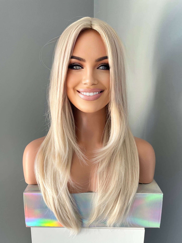 Blonde wig on a mannequin head against a gray background